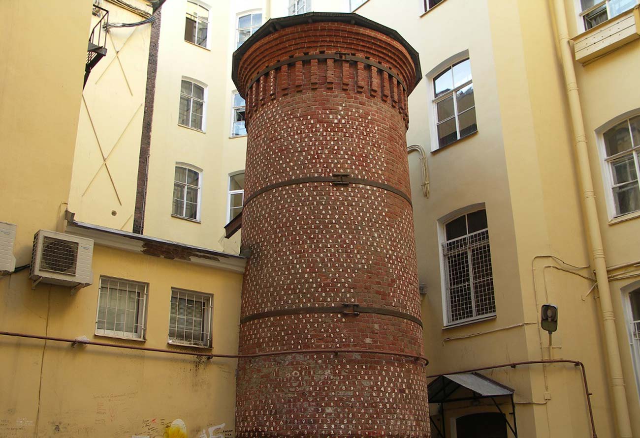Висока кругла вежа з червоної цегли списана цифрами